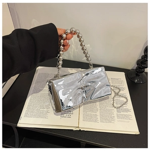Detail of silver mirror handbag featuring metallic beads handle and crumpled texture