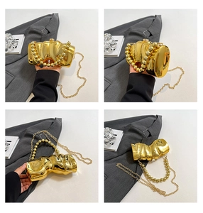 Nahaufnahme der goldenen Clutch mit Wellenstruktur, Perlengriff und Metallkette