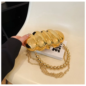 Close-up of gold pleated acrylic evening bag with beaded and metal chain straps