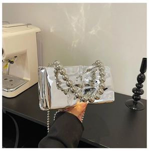 Detail view of silver mirror handbag featuring liquid metal folds and oversized bead chain