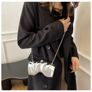 Nahaufnahme einer silbernen unregelmäßigen Metallic-Clutch mit flüssigen Falten und Kette