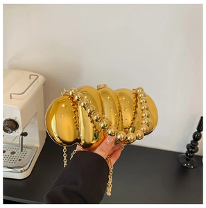 Detail of gold wavy acrylic evening clutch featuring large bead handle and metallic finish