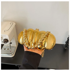 Macro view of golden shell-shaped acrylic evening bag with bold beaded handle