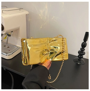 Detail of gold wrinkled metallic handbag with elegant bead chain strap for women