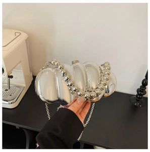 Detail of silver metallic textured evening bag with unique wavy design and chain strap