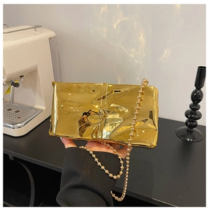 Close-up of golden metallic quilted clutch bag with ball chain and pleated texture