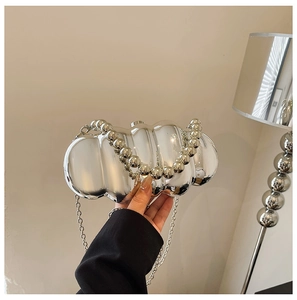 Detail of silver wavy acrylic evening bag with beaded handle and metal chain strap