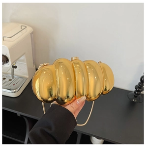 Macro shot of the luxury gold caterpillar clutch bag with glossy pleated metal texture