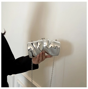 Nahaufnahme einer silbernen Clutch mit unregelmäßigen Falten und eleganter Kette