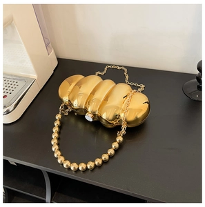 Detailed view of golden acrylic clutch bag with pearl bead handle and chain strap
