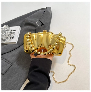 Detail der goldenen Spiegel-Clutch mit Wellenstruktur und rundem Perlen-Griff für den Abend
