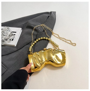 Detail der unregelmäßigen goldfarbenen Abendtasche mit Perlengriff und Kettenriemen
