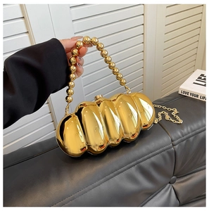 Close-up of gold caterpillar acrylic evening bag with wavy texture and beaded handle