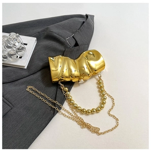 Makroaufnahme einer goldenen Clutch mit Wellentextur auf einer grauen Anzugsjacke