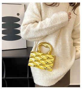 Detailed view of luxury gold mirror metal box bag with quilted texture and chain