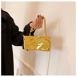 Detailed close-up of metallic gold pleated bag with pearl handle and chain strap