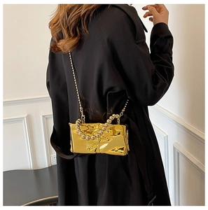 Close-up of golden mirror acrylic mini bag with beaded handle on a black coat
