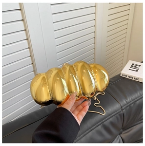 Detail view of the caterpillar-shaped gold acrylic evening clutch with metal chain strap