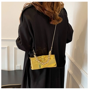 Detail view of a gold metallic mirror shoulder bag featuring a beaded handle and chain strap
