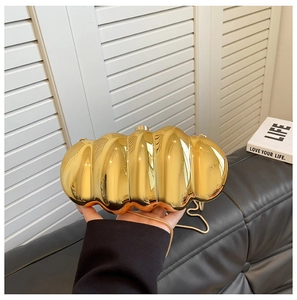 Macro shot of gold caterpillar acrylic evening bag with wavy texture and chain strap