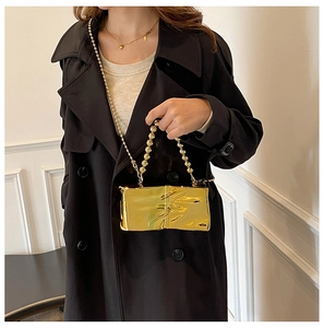 Close-up of a gold metallic box bag with unique pleated texture and beaded chain strap