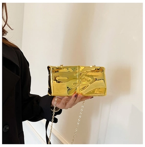 Detail of elegant gold wrinkled texture evening bag with a metallic chain strap