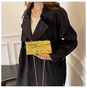 Close-up of golden metallic clutch bag with wave pleats and a fine chain strap