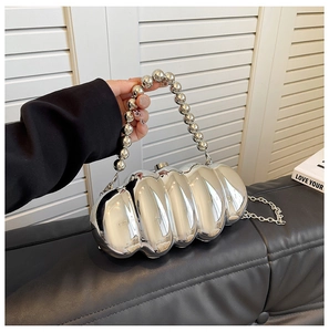 Close-up of metallic silver wavy evening bag with bead handle on a black leather bench