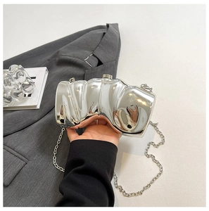 Detail einer silbernen unregelmäßigen Abendtasche mit Metallic-Finish und Metallkette
