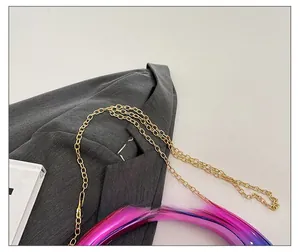 Close-up of golden metal chain strap on a purple gradient moon-shaped evening bag
