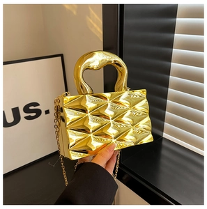 Detailed view of the gold box bag's reflective rhombic texture and metal top handle
