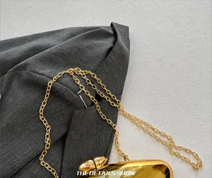 Detail showing the exquisite gold chain strap and glossy metallic texture of the handbag
