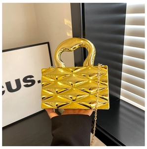 Macro shot of gold metallic box bag with quilted lattice texture and chain strap