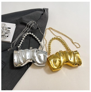 Detail von metallischen Gold- und Silber-Clutch-Taschen mit Faltenstruktur und Perlen