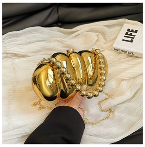 Detail of a gold pumpkin-shaped evening clutch bag with beaded handle and chain