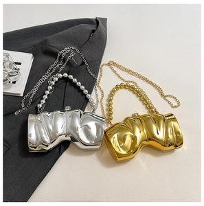 Detail von wellenförmigen Metallic-Abendtaschen in Gold und Silber mit Kettenriemen