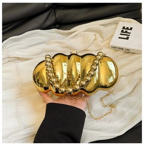 Macro detail of gold ripple acrylic evening bag with metallic mirror finish and bead handle