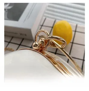 Close-up of golden metal clasp and ring handle on white spherical evening bag