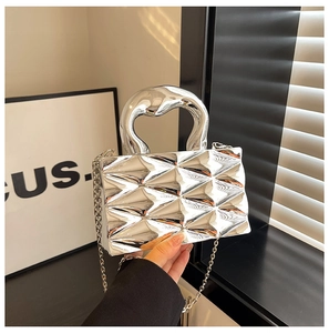 Detail of silver metallic box bag featuring 3D quilted texture and thick curved handle