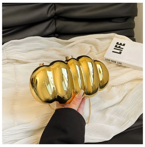 Close-up of golden metallic clutch bag with unique wavy accordion pleats and chain strap
