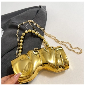 Detail einer goldenen Metallic-Clutch in Wellenform mit Perlen Griff und Kettenriemen