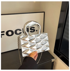 Macro detail of silver geometric box bag with 3D diamond pattern and polished finish