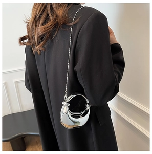 Silberne Metallic-Halbmondtasche mit Rundgriff, getragen zu einem schwarzen Blazer