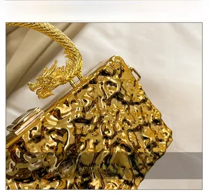 Macro detail of luxury gold acrylic mirror clutch bag with an ornate dragon handle design
