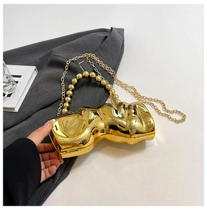 Detailansicht der goldenen Abendtasche mit Wellenstruktur, Perlengriff und Metallkette