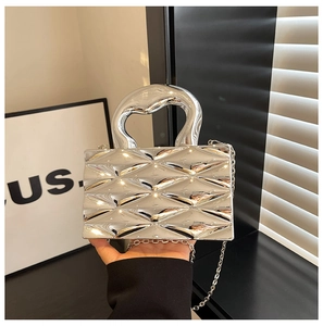 Detailed view of silver metallic bag with geometric diamond texture and curved handle