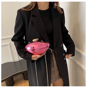 Close-up of vibrant pink mirror-finish heart clutch with elegant gold chain strap