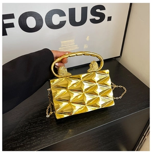 Detail view of a gold geometric box clutch with lion head handle and fine chain strap