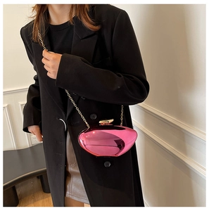 Chic metallic pink hard shell clutch with gold chain strap shown on a black suit