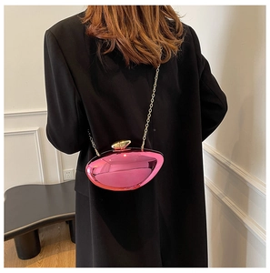 Close-up of metallic pink pebble-shaped clutch bag with golden chain on a black coat